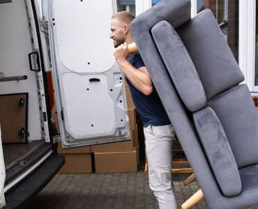 Möbellift Offenbach: Helfer tragen ein graues Sofa aus einem Transporter
